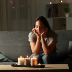Woman staring at candles on her coffee table during blackout, maybe a vulnerable person