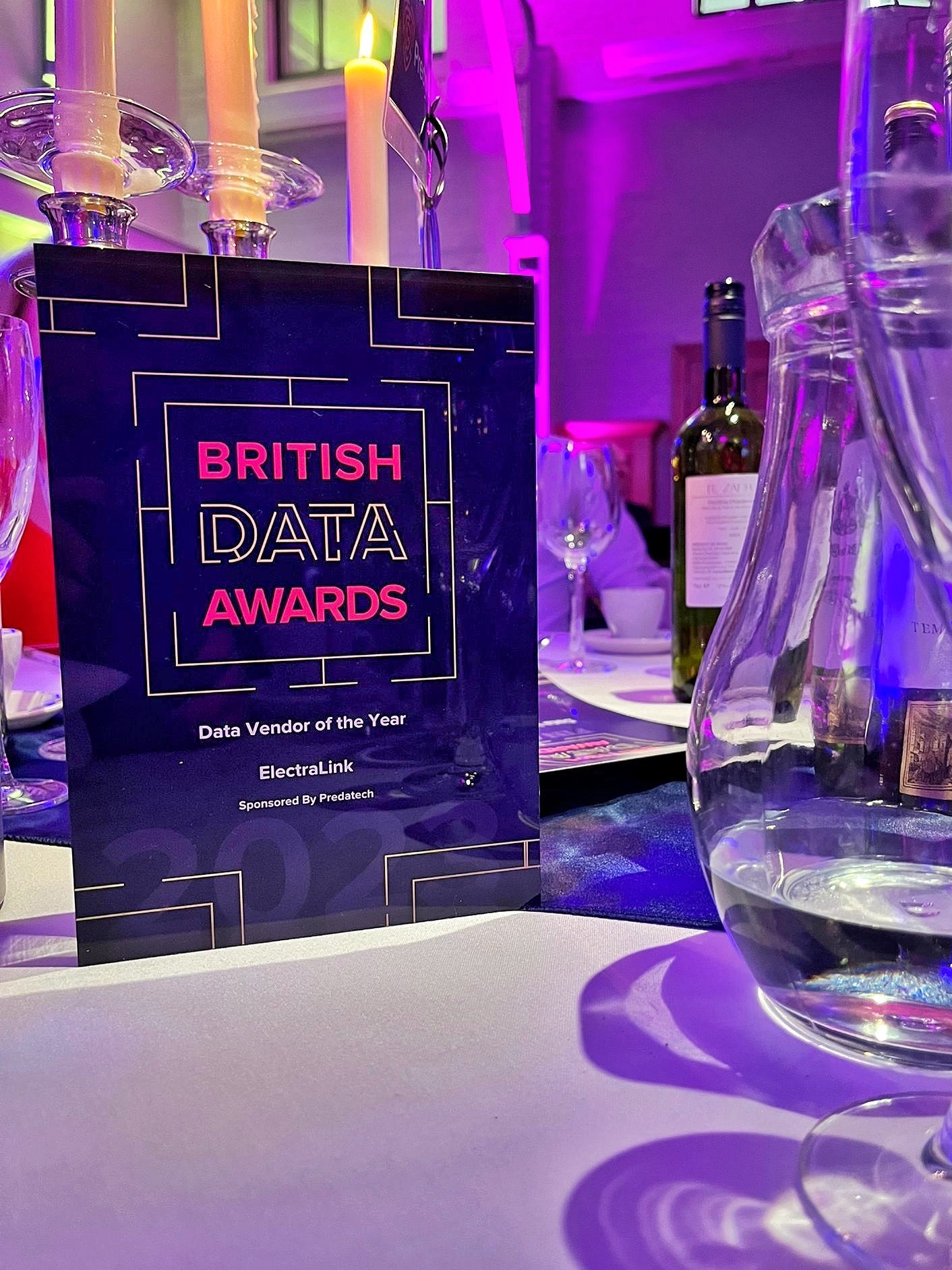 British Data Award trophy on a table beside glassware on a white tablecloth.